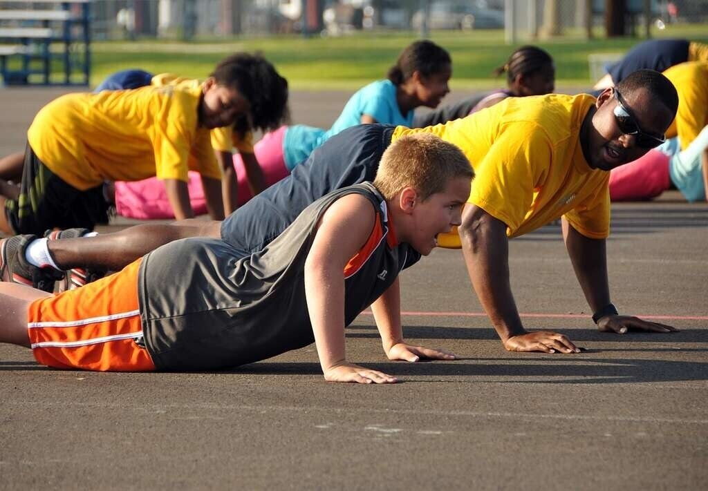 Kids and adults doing plank pose together outdoors