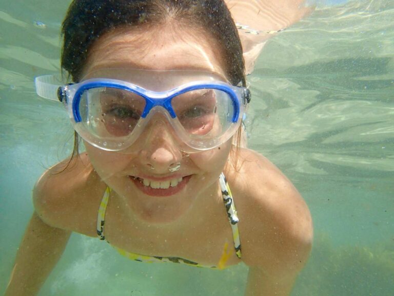 Little girl swimming underwater with goggles - 10 of the Best Pool Diving Games for Kids