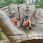 Two young boys with baseball gloves sitting inside statue of baseball glove - The 5 Best Youth Left Handed Baseball Gloves