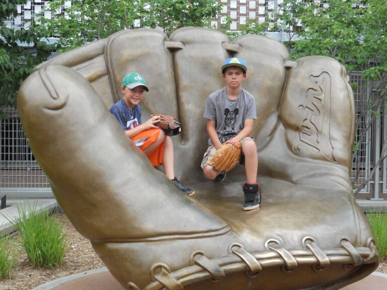 Two young boys with baseball gloves sitting inside statue of baseball glove - The 5 Best Youth Left Handed Baseball Gloves