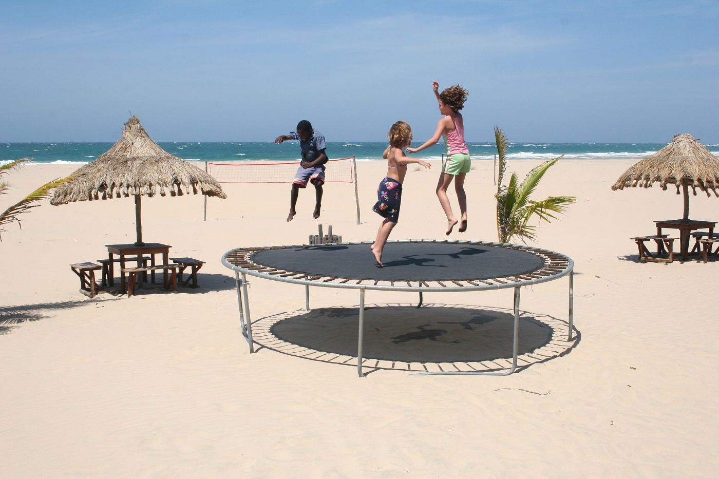 Three kids jumping on trampoline on beach - How to Keep a Trampoline from Blowing Away: 7 Basic Steps