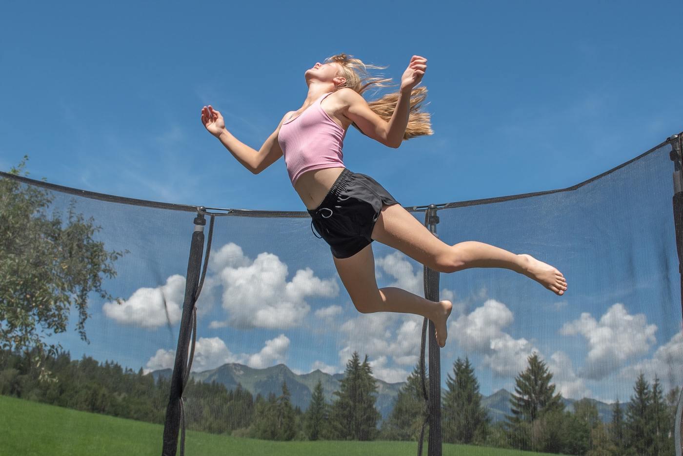 Girl jumping on trampoline with enclosure netting - How to Keep a Trampoline from Blowing Away: 7 Basic Steps
